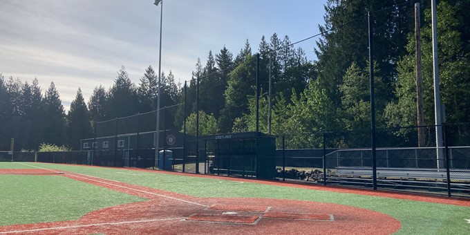 Corner of baseball diamond at Eastlake Community Sports Field 3 in Sammamish with bleachers, dugout, night lights, and trees in the background.