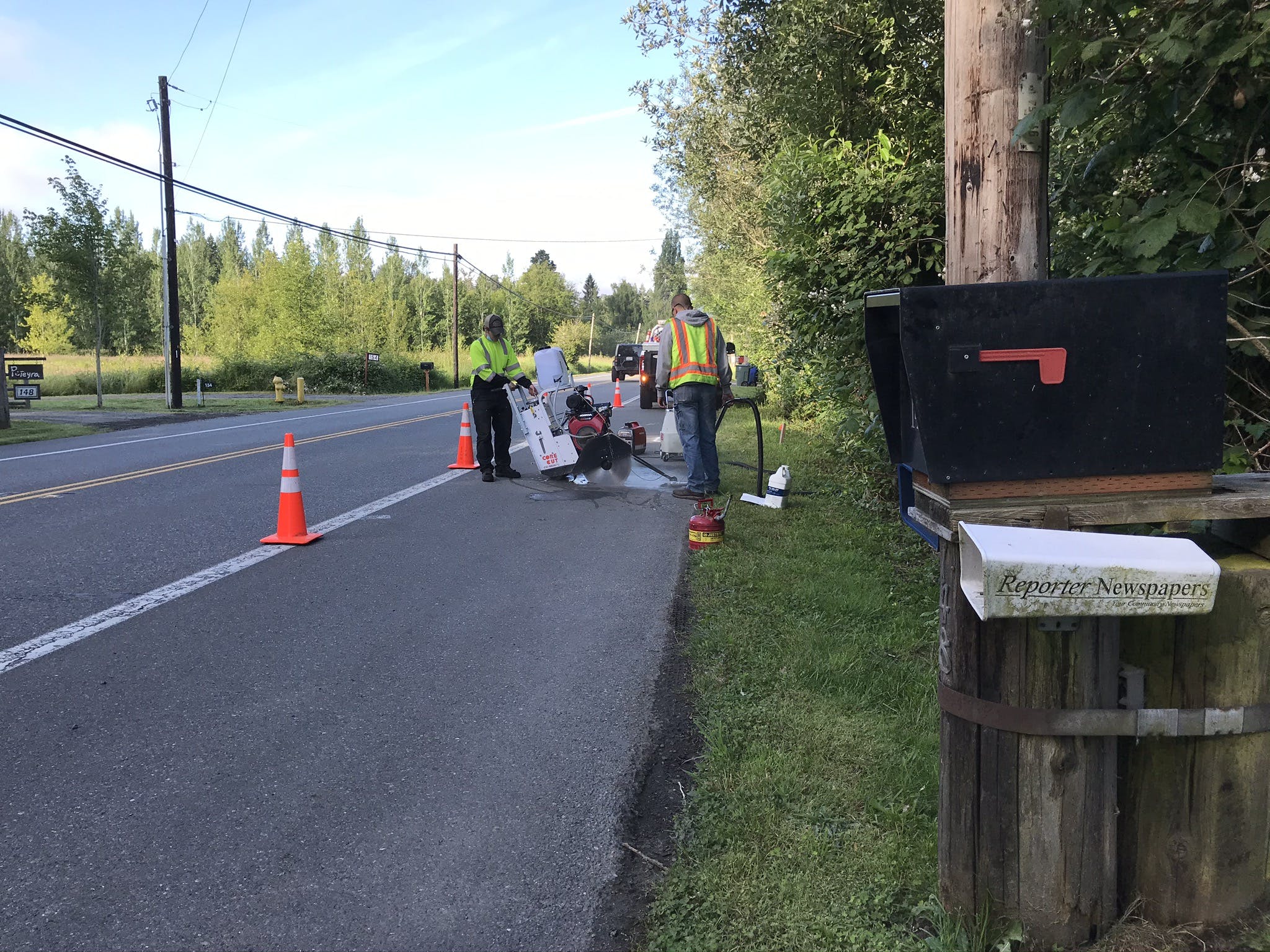 Sammamish Maintenance Crew saw cutting the pavement on the shoulder of the road next to orange cones as part of the Ebright Creek Fish Passage project. 