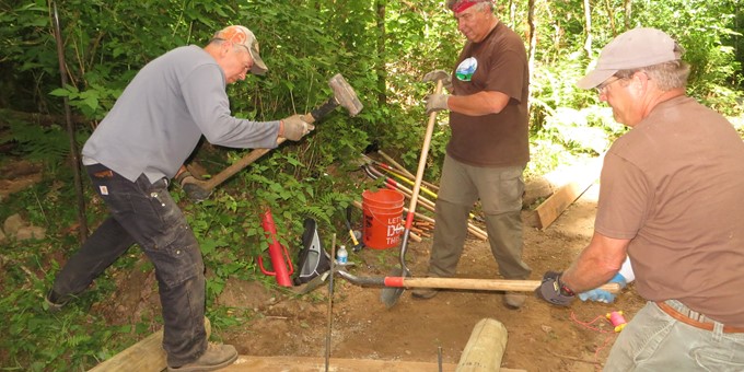 Three Sammamish stewards hard at work with shovels in a wooded area, helping create a boardwalk trail.